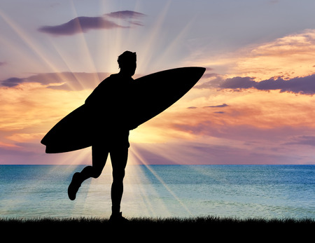 Sports concept. Silhouette of a surfer on the beach at sunset sea background