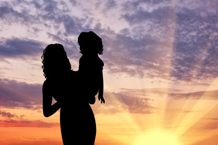 Silhouette mother with a child at sunsetの写真素材