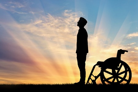 Concept of disability and disease. Silhouette of disabled person who stood out of the wheelchair on the sunset backgroundの写真素材
