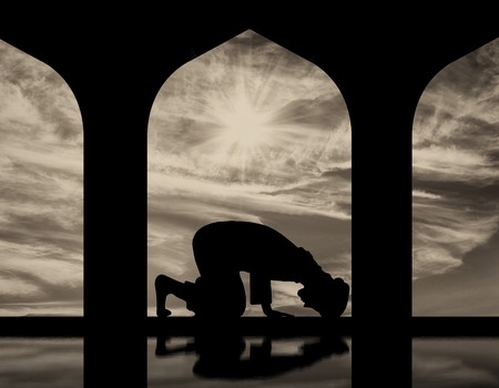 The concept of the Islamic religion. Silhouette of man praying at the Town Hall and reflectionの写真素材