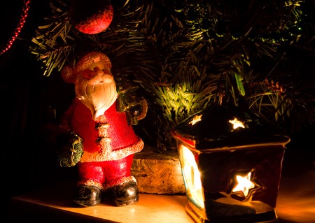 Toy Santa Claus on a background of branches of Christmas trees and lampの写真素材