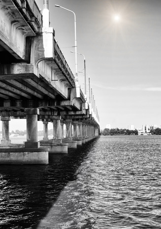 Long concrete bridge across the river against the backdrop of a cloudy skyの写真素材