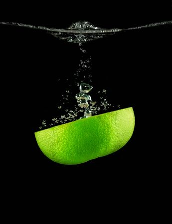 Half a lime fruit in water on a background of bubbles