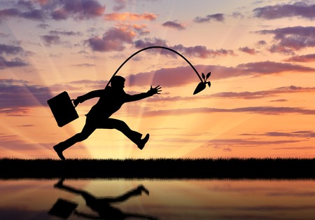 Silhouette of businessman running for the carrot and reflection in water. Concept of money and businessの写真素材