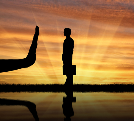 Discrimination and racism concept. Silhouettes of hands stops a man on the sunset backgroundの写真素材