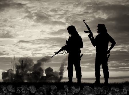 Terrorism and conflict. Skulls and bones underfoot two terrorists on the background of explosions and smokeの写真素材