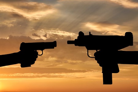 Terrorism and conflict. Weapons in the hands of people at sunset backgroundの写真素材