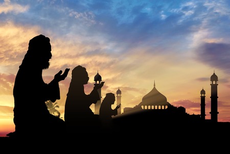 Islamic religion. Muslims Praying on a background of a mosque at sunsetの写真素材
