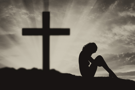 Atheism. Atheist woman sits with his back to the crossの写真素材