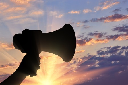 Megaphone. The loudspeaker in his hand on a sunset backgroundの写真素材