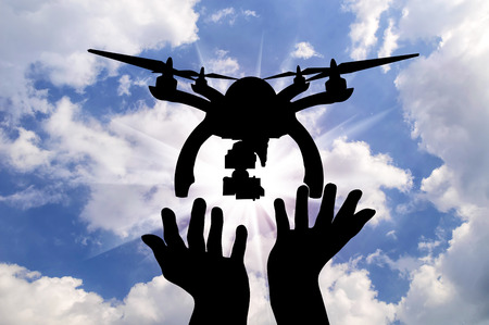 Silhouette takeoff drone of human hands against the skyの写真素材