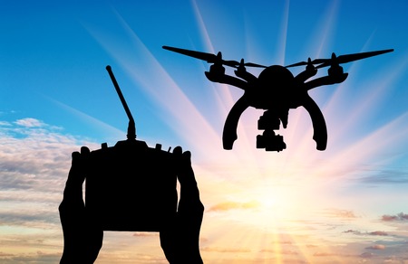 Silhouette flying drones and hands with remote control outdoors. Concept quadrocoptersの写真素材
