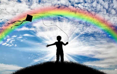Silhouette child playing with kite on street day and rainbow. Concept childhood and happinessの写真素材