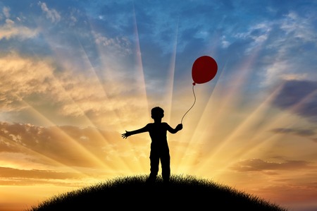 Boy playing with balloon on hill sunset. Concept childhoodの写真素材