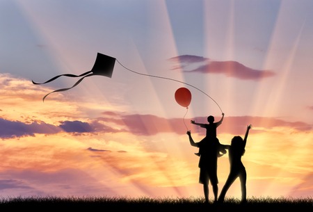 Young family playing outdoors with kite and child holding balloon . ?oncept happy familyの写真素材