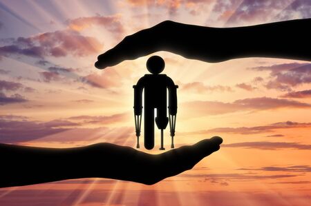 Icon disabled on crutches with prosthesis in hands on sunset background. Concept protection of people with disabilitiesの写真素材