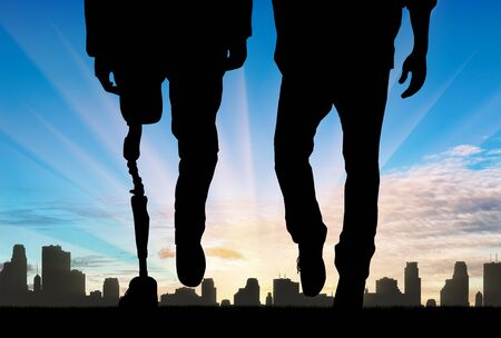 Leg man with prosthetic and normal legs on background city and sunset. Concept disabled personの写真素材