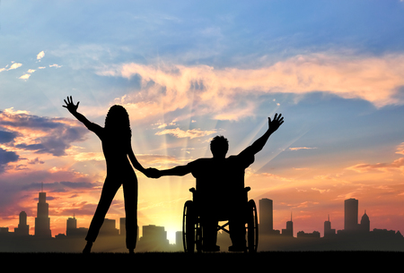 Happy disabled person in a wheelchair, holding his hands Maritime Day girlfriend. The concept of happy people with disabilities and the familyの写真素材