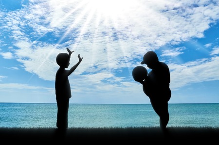 Fat man and a normal boy, playing ball against the background of the sea. obesity conceptの写真素材