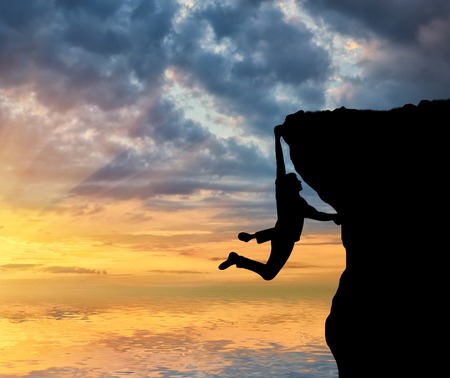 Climbing climber on top of a mountain on a background of sea sunset. Concept of motivation and purposefulnessの写真素材