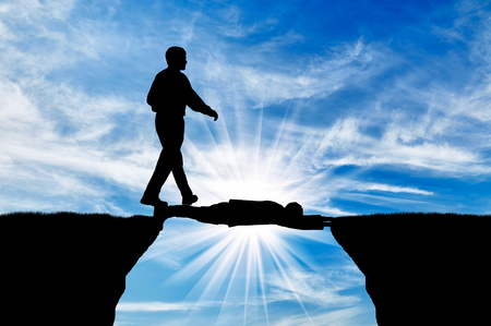 Man walking on man lying on precipice. Concept of social inequalityの写真素材