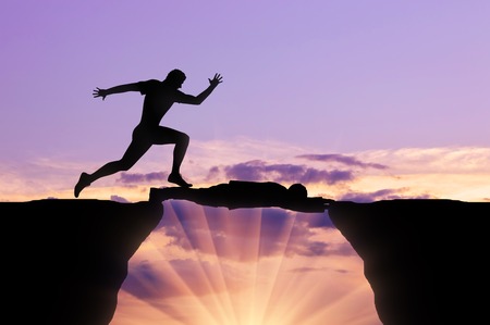 Man runs through a man lying on precipice. Concept of competitionの写真素材