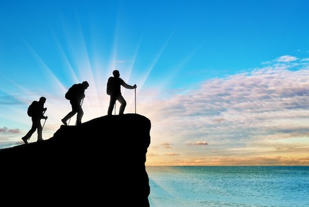 Silhouette climbers ascending to top of mountain on background of the sea. Concept teamworkの写真素材