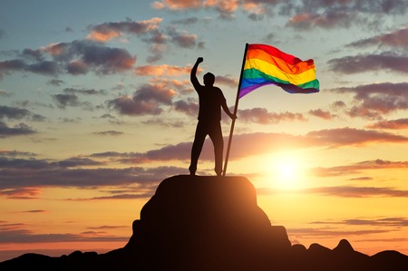 Silhouette with the gay rainbow flag on a mountain top. Concept rights and freedoms of gaysの写真素材