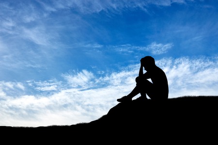 Child abuse and violence. Silhouette of a crying lonely boy against skyの写真素材