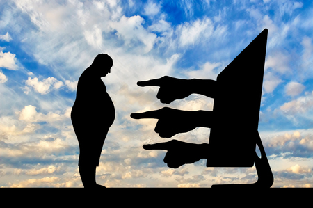 Cyberbullying. Hands from computer showing with fingers on fat manの写真素材