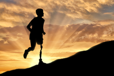 Concept of disability. Man with prosthetic leg running up the hillの写真素材