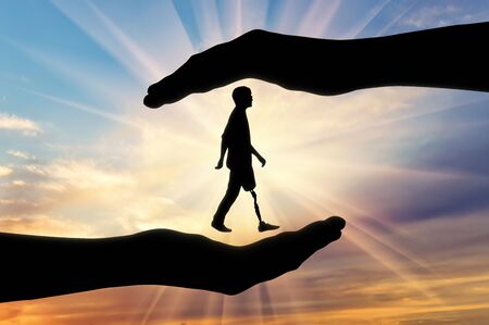 Concept of aid and care for disabled with a prosthetic leg. A disabled person with a prosthetic leg in hands of manの写真素材