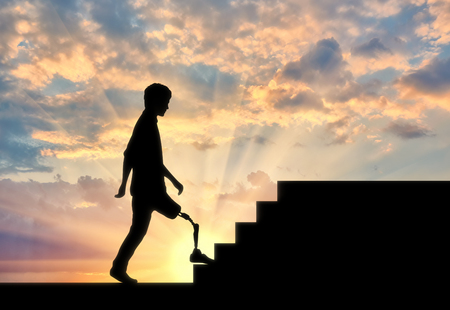 Disabled Walking with a prosthetic leg climbs the stairs at sunsetの写真素材
