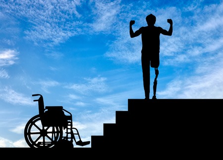 Disability and rehabilitation. Happy disabled man with a prosthetic leg walked up the stairs, and a wheelchairの写真素材