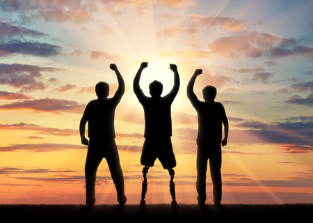 People with disabilities in society concept. Happy disabled man with a prosthetic leg standing and his friends at sunsetの写真素材
