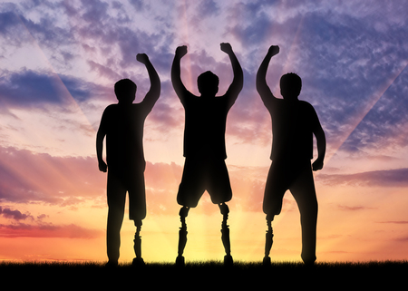 Disability concept. Happy disabled with a prosthetic leg standing on sunset backgroundの写真素材