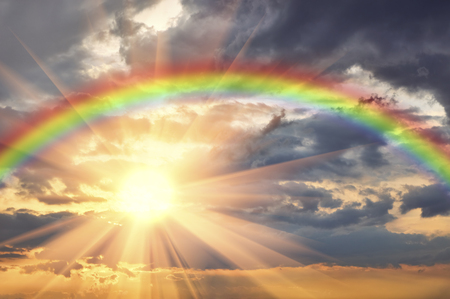 Rainbow in the beautiful sky at sunset and the bright sun with raysの写真素材