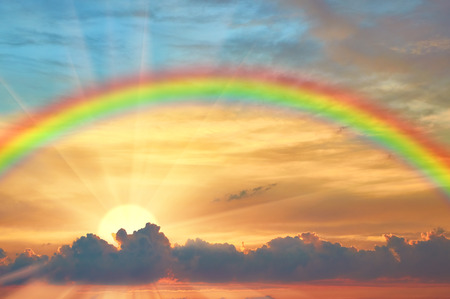 Rainbow in the beautiful sky at sunset and the bright sun with raysの写真素材