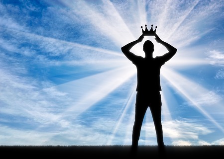 Concept of narcissism and selfishness. Silhouette of a selfish and narcissistic man reconciling his own crownの写真素材