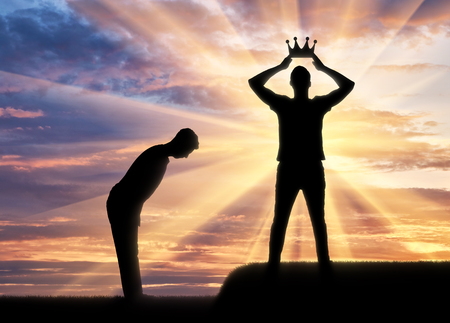 Concept of selfishness and narcissistic. Silhouette of a man dresses his crown, and a servant bows to himの写真素材