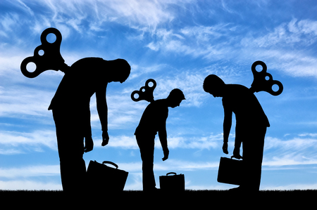 The concept of a tired business team from work. The silhouette of the tired workers with a clockwork mechanism on the backの写真素材