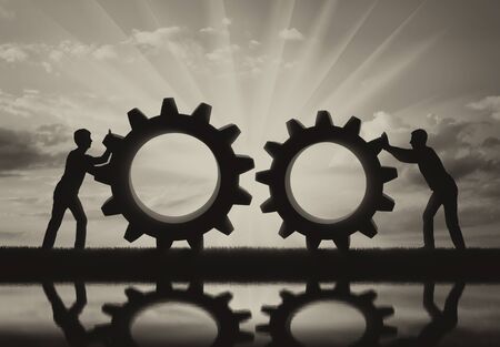 Silhouette of two people who want to connect the two gears in a single mechanism. The concept of cooperation in businessの写真素材