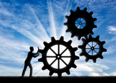 Silhouette of a businessman fixing a mechanism of gears. Establishment of business conceptの写真素材