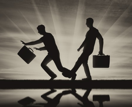 Silhouette of a businessman who does meanness to another businessman. The concept of a rival in businessの写真素材