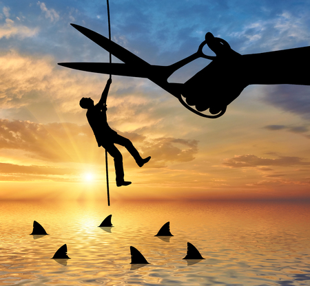 Scissors cut the rope on which hangs a businessman and underneath sharks. The concept of risk in businessの写真素材
