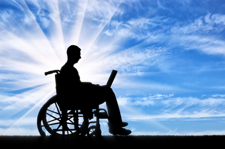 A disabled person in a wheelchair working with a laptop in his hands. The concept of the opportunity to work for people with disabilitiesの写真素材