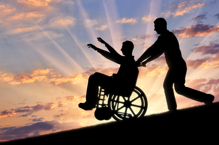 Happy disabled person in a wheelchair having a great time with a friend. The concept of care and assistance for the disabledの写真素材