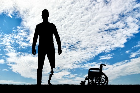 A man with a prosthetic leg standing on the background of a wheelchair. The concept of prosthetic legsの写真素材