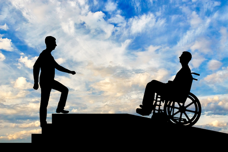 A disabled person in a wheelchair climbs up the ramp, and healthy man on the stairs. The concept of helping the disabled to moveの写真素材