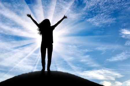 Silhouette of happy woman with outstretched hands up, standing at sunset. The concept of successful...